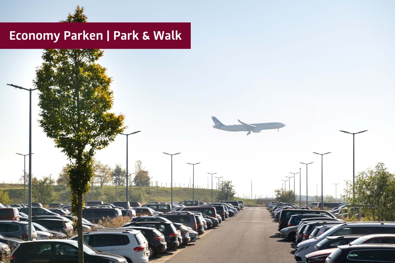 Parkplatz P107 mit parkenden Autos und einem Flugzeug im Hintergrund das fliegt