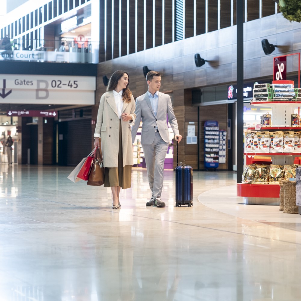 Passengers stroll through the marketplace in Terminal 1 with hand luggage suitcases