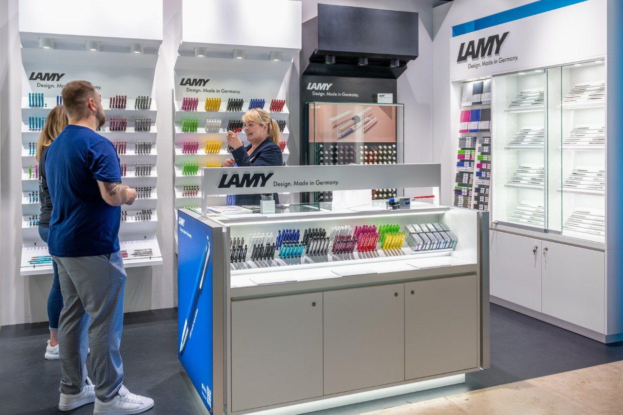 1 employee advises 2 customers in the store. The display in the background.