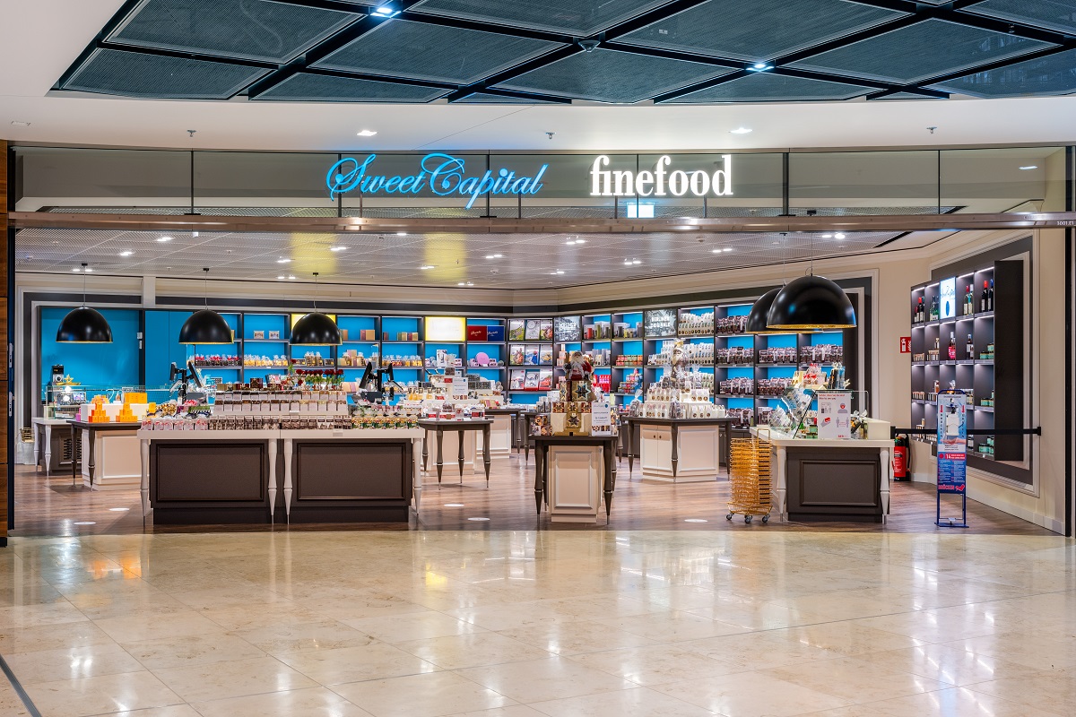 View of the Sweet Capital store from outside. Numerous counters in the foreground. Wall shelves in the background.