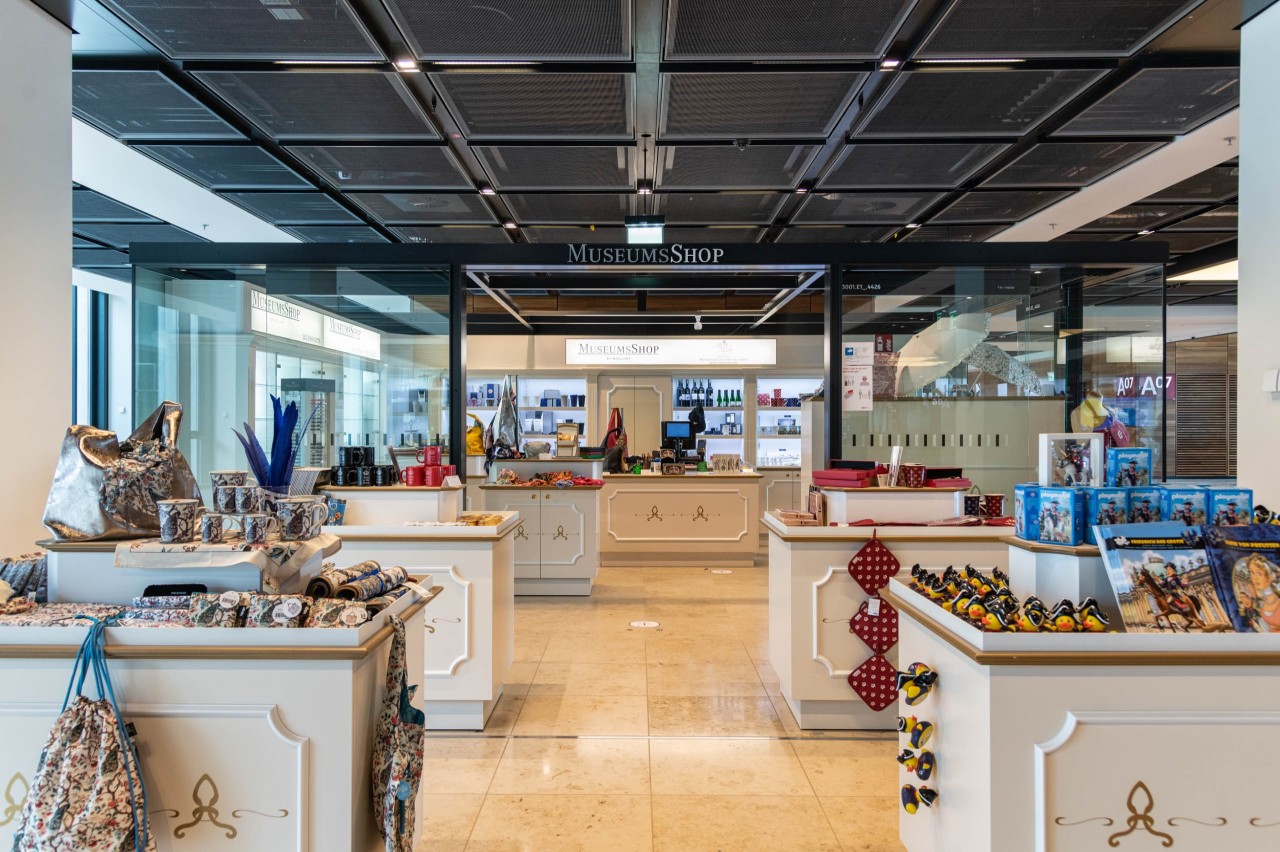 Numerous counters with display in the MusseumsShop store. Wall shelves in the background.