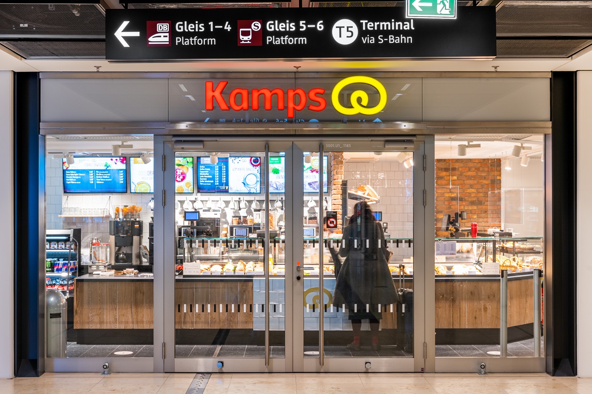View of the Kamps bakery from outside. The door is closed. Displays above the counter with offers.