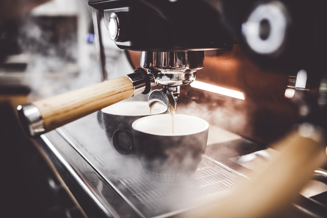 Coffee flows from a machine into two cups