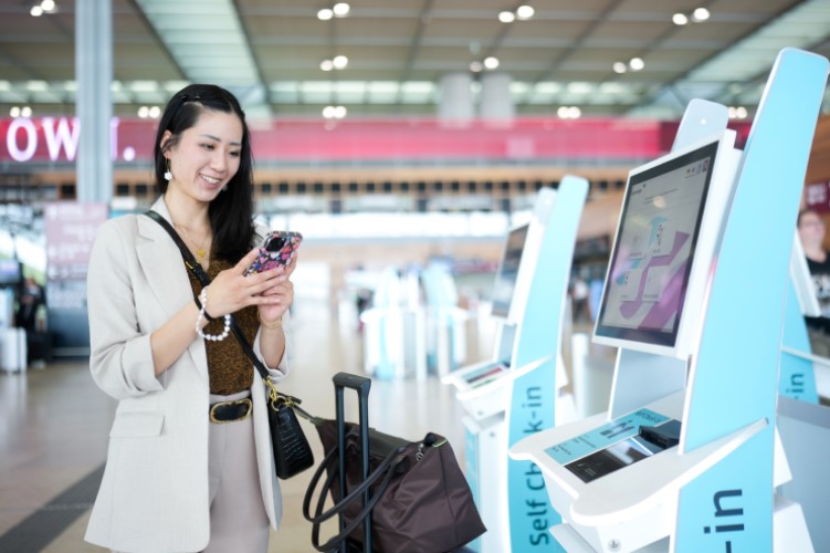 Woman with suitcase and cell phone in front of vending machine