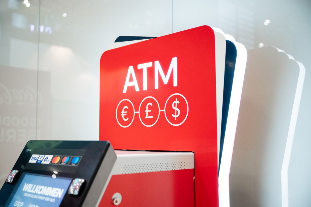 Red ATM in front of a light-colored wall.