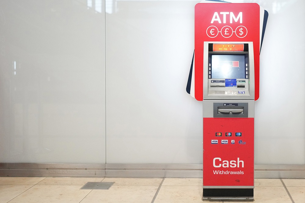 Red ATM in front of a light-colored wall.