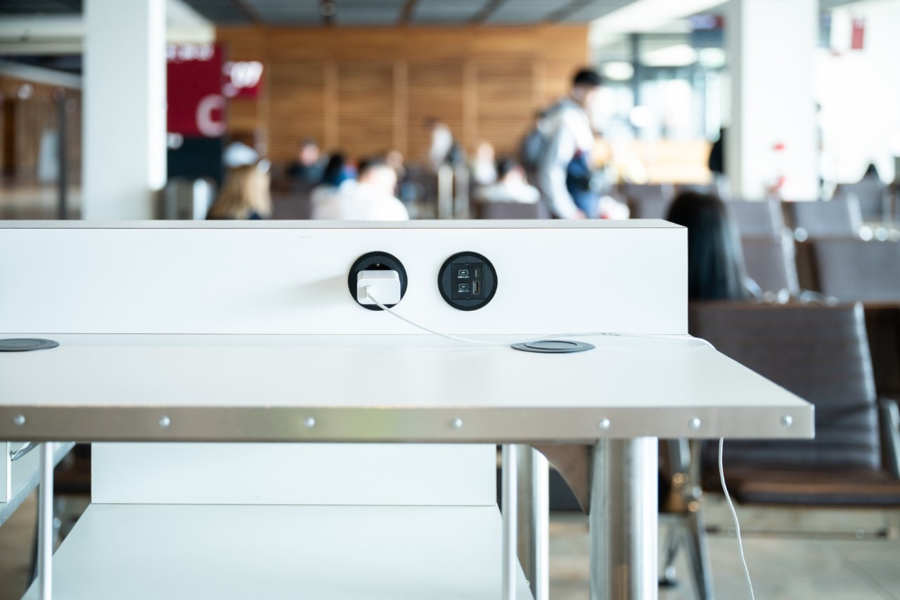 Close-up of a work area with power sockets. People waiting in the gate.