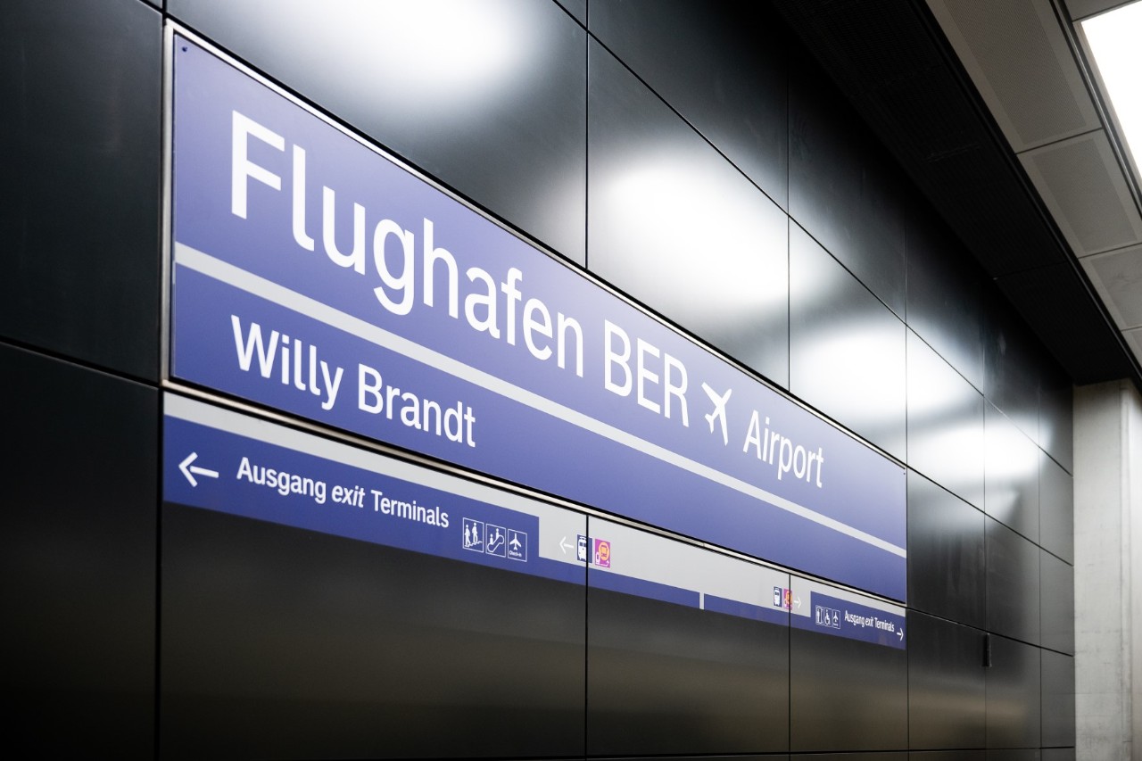 Sign with the name of the railway station on a black wall.