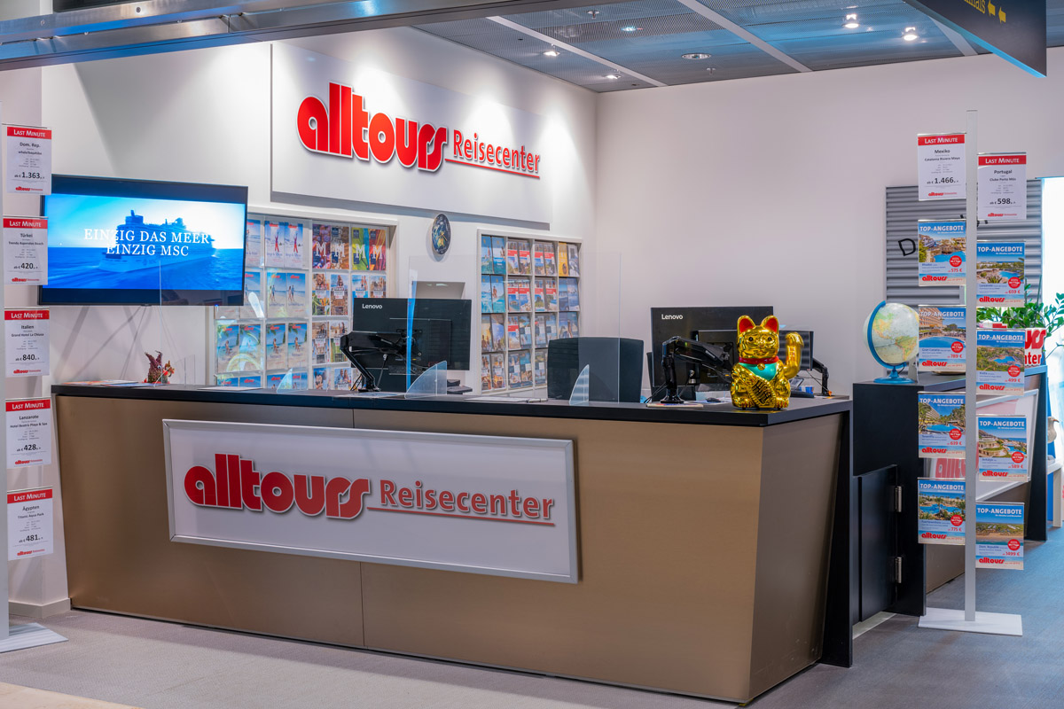 View from outside onto the counter of the alltours travel center. Travel offers on the wall in the background.
