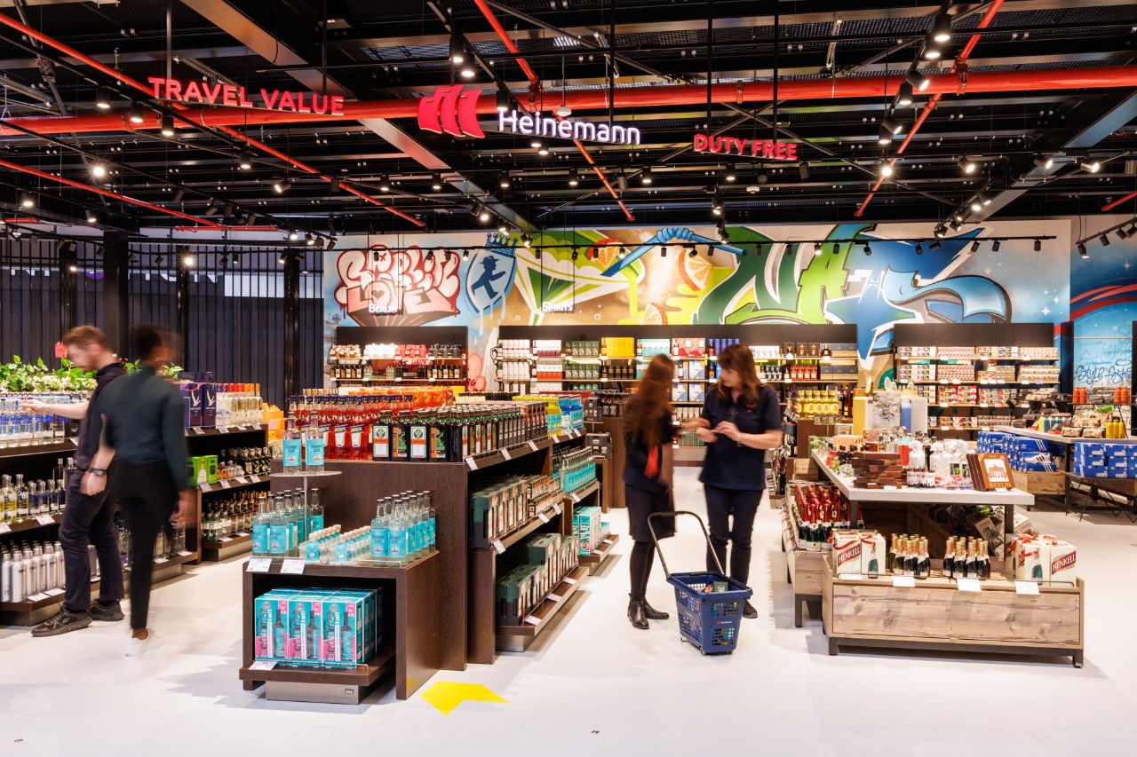 Several people store in the store. Drinks and food on the shelves.