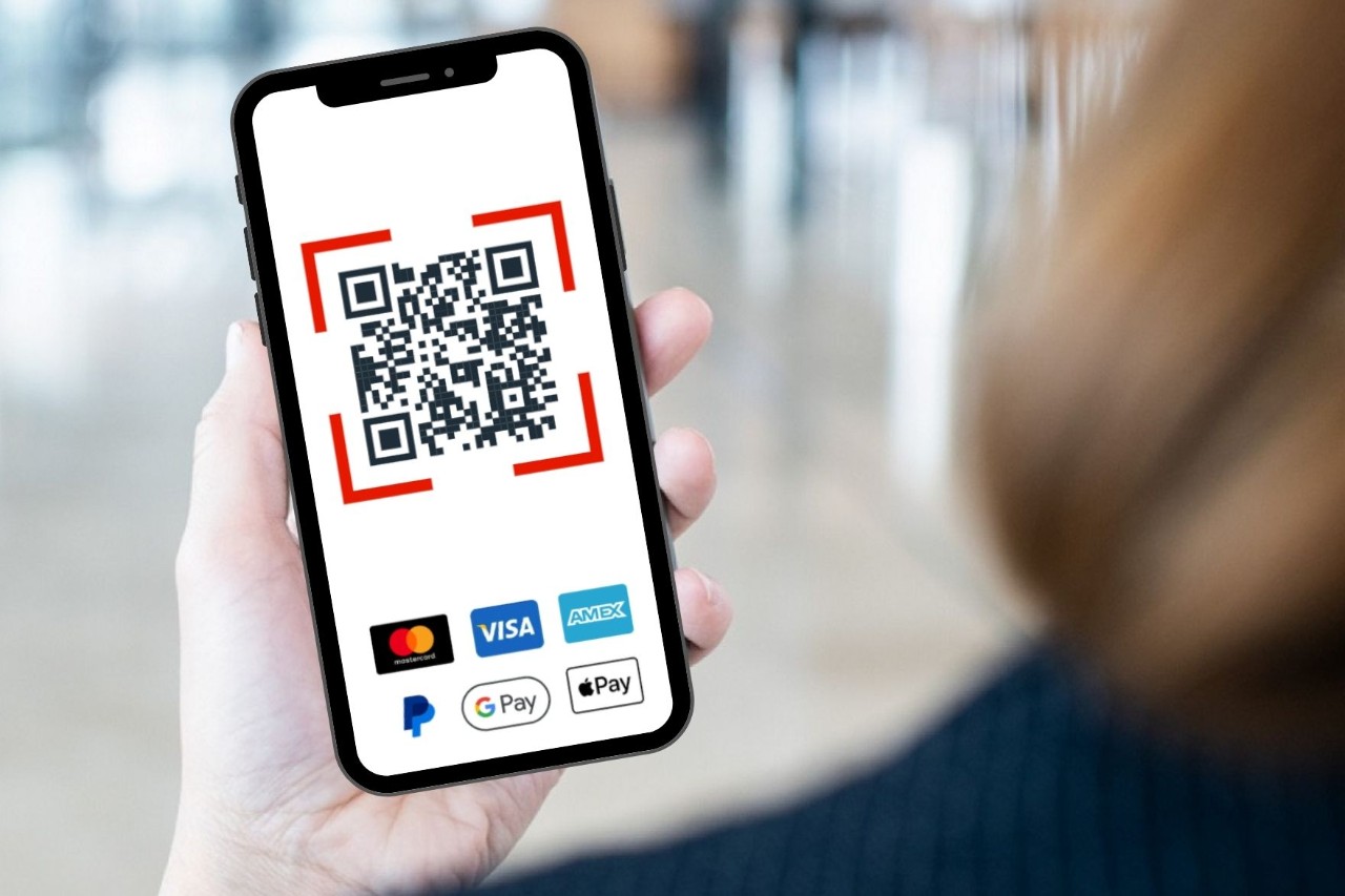 Woman holding a cell phone. The cell phone displays a QR code for paying for a parking ticket.