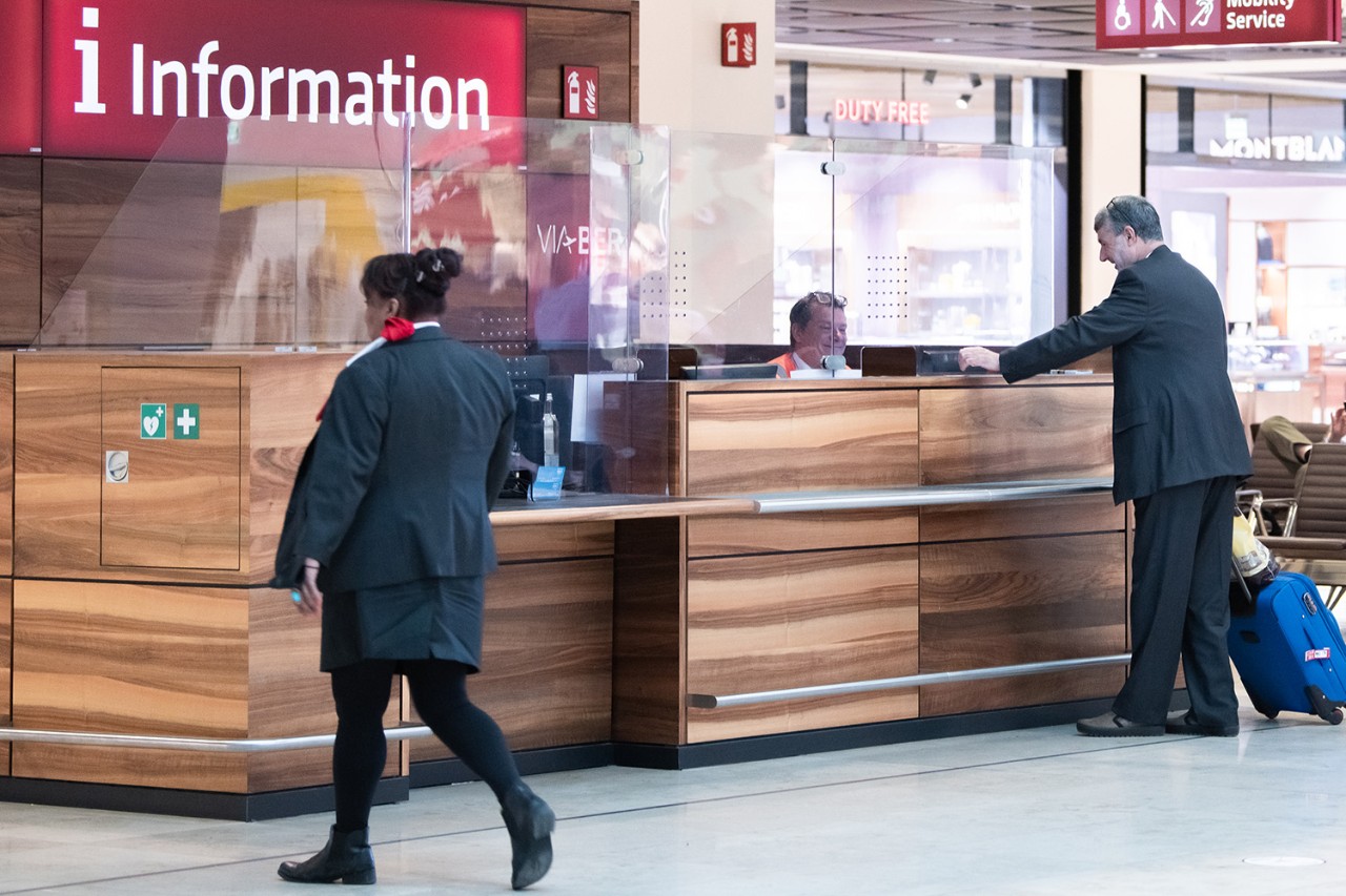 1 person stands at the airport information desk and receives information.