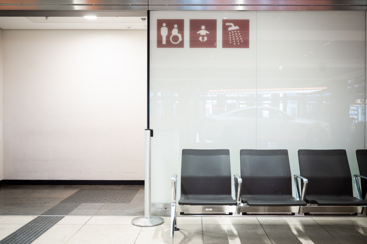 Access to the shower is signposted with pictograms. A row of seats in front.