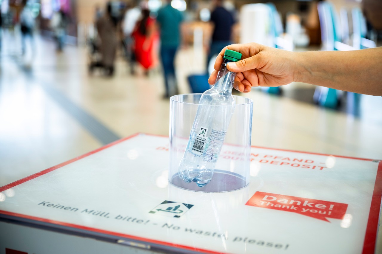  Donate Your Deposit Bin. Hand throwing a bottle into the bin.