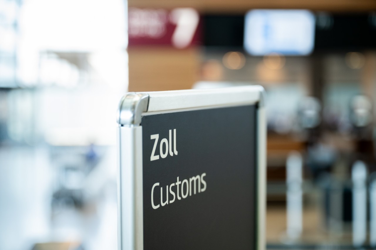 Sign with the imprint “ Zoll, Customs”. The background is blurred.