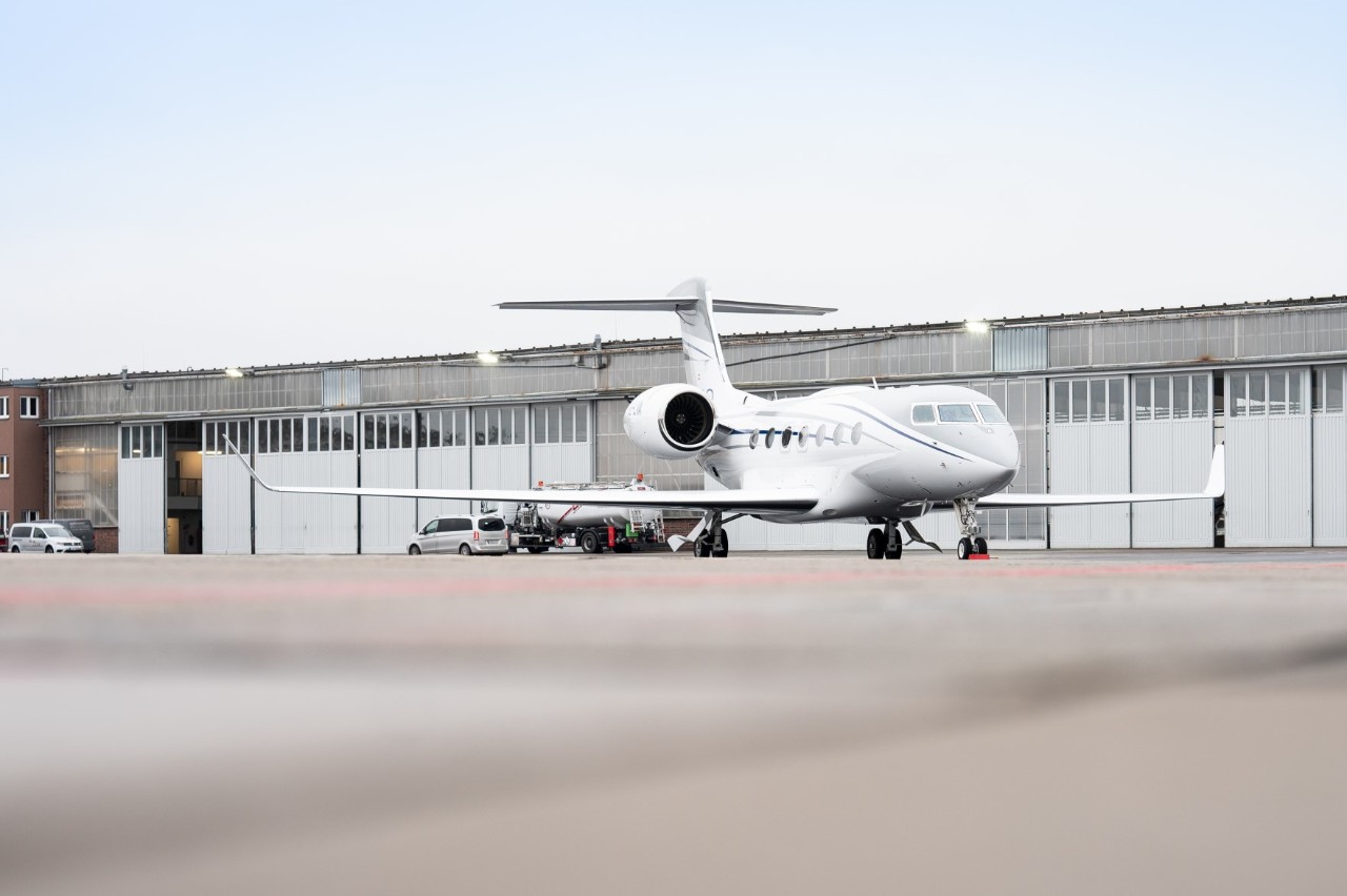 Business aircraft on the apron. Behind it a hangar.