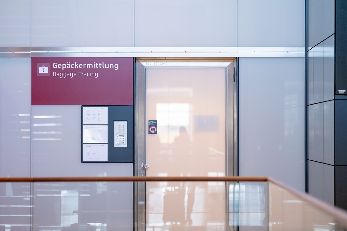 Frosted glass door. Next to it a sign for baggage tracing