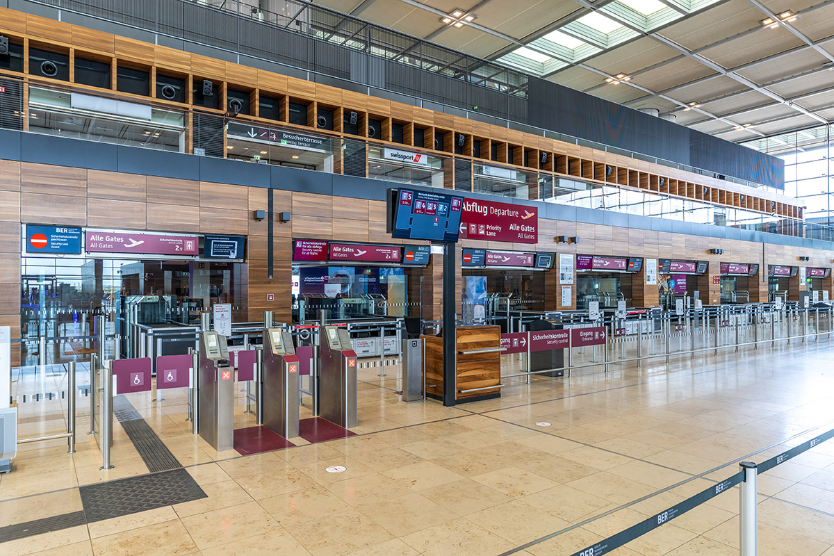 Security screening lanes in Terminal 1 of BER Airport, with monitors above 
