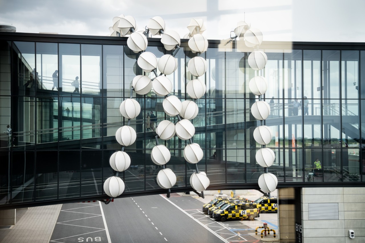 Artwork Gadget: Close-up of a glass facade with reflective, white spherical sculptures arranged vertically.