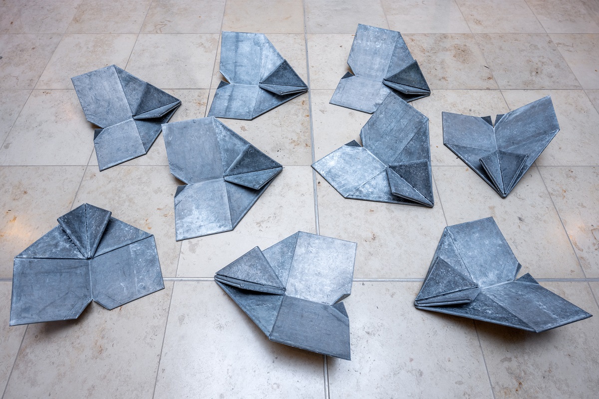 L’Albatros’ sculpture of nine floating paper airplanes in the entrance area of Terminal 1 at BER. Modern glass facade of the terminal in the background.