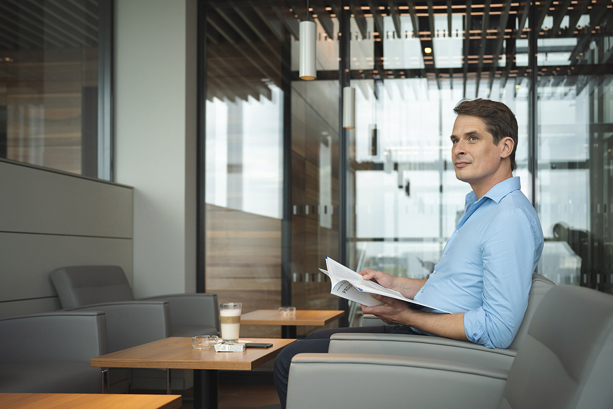 Man sits in a lounge chair and holds a brochure in his hand.