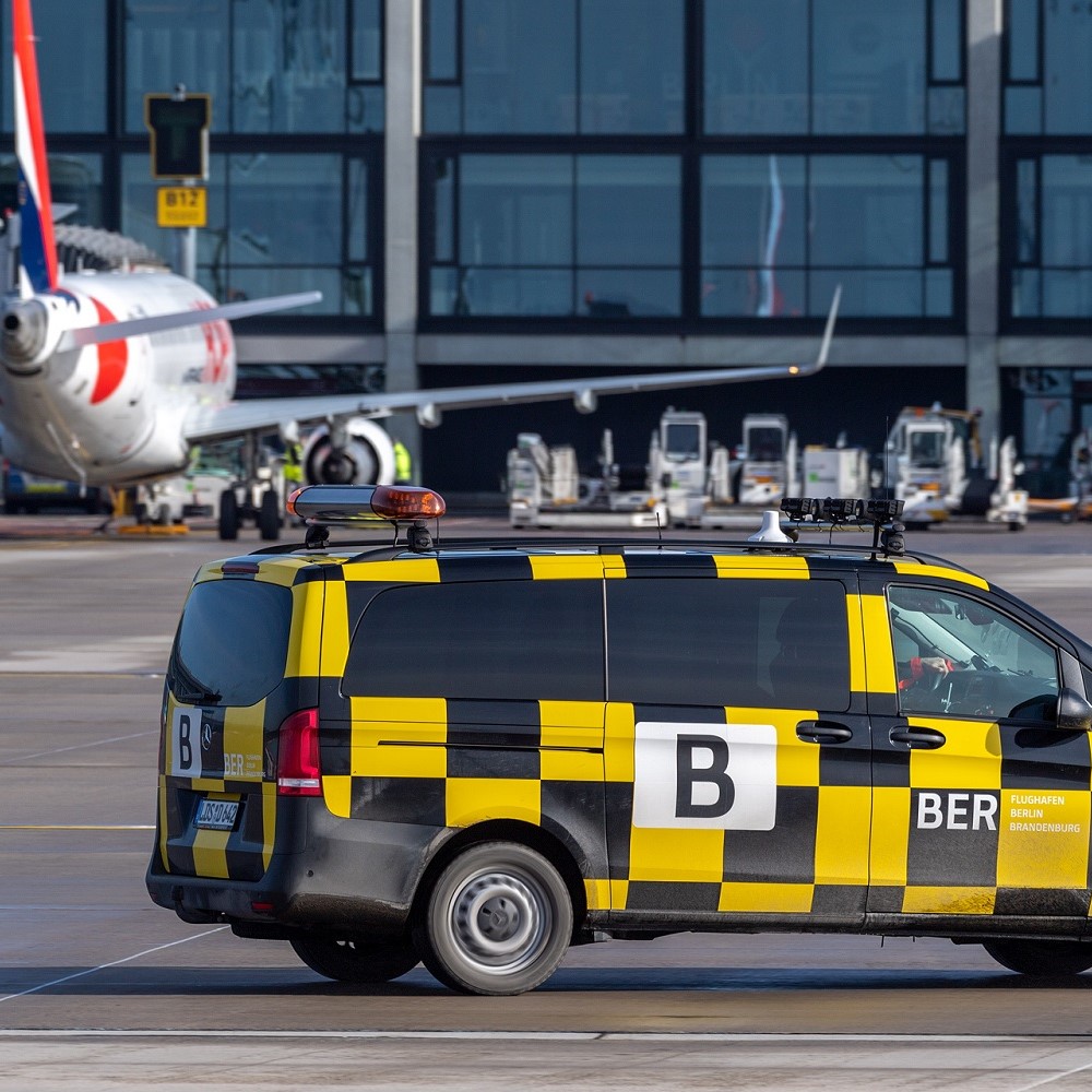Follow-me vehicle on the BER apron. Behind it an airplane and Terminal 1.