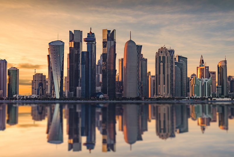 Skyline von Doha im Sonnenaufgang, Spiegelung Skyline im Wasser,  gelber Himmel