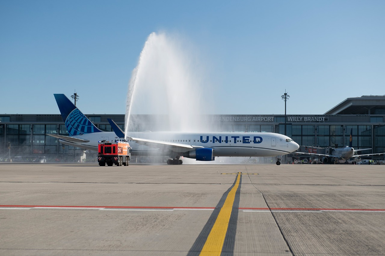 United Airlines plane during water fountain by airport fire department.