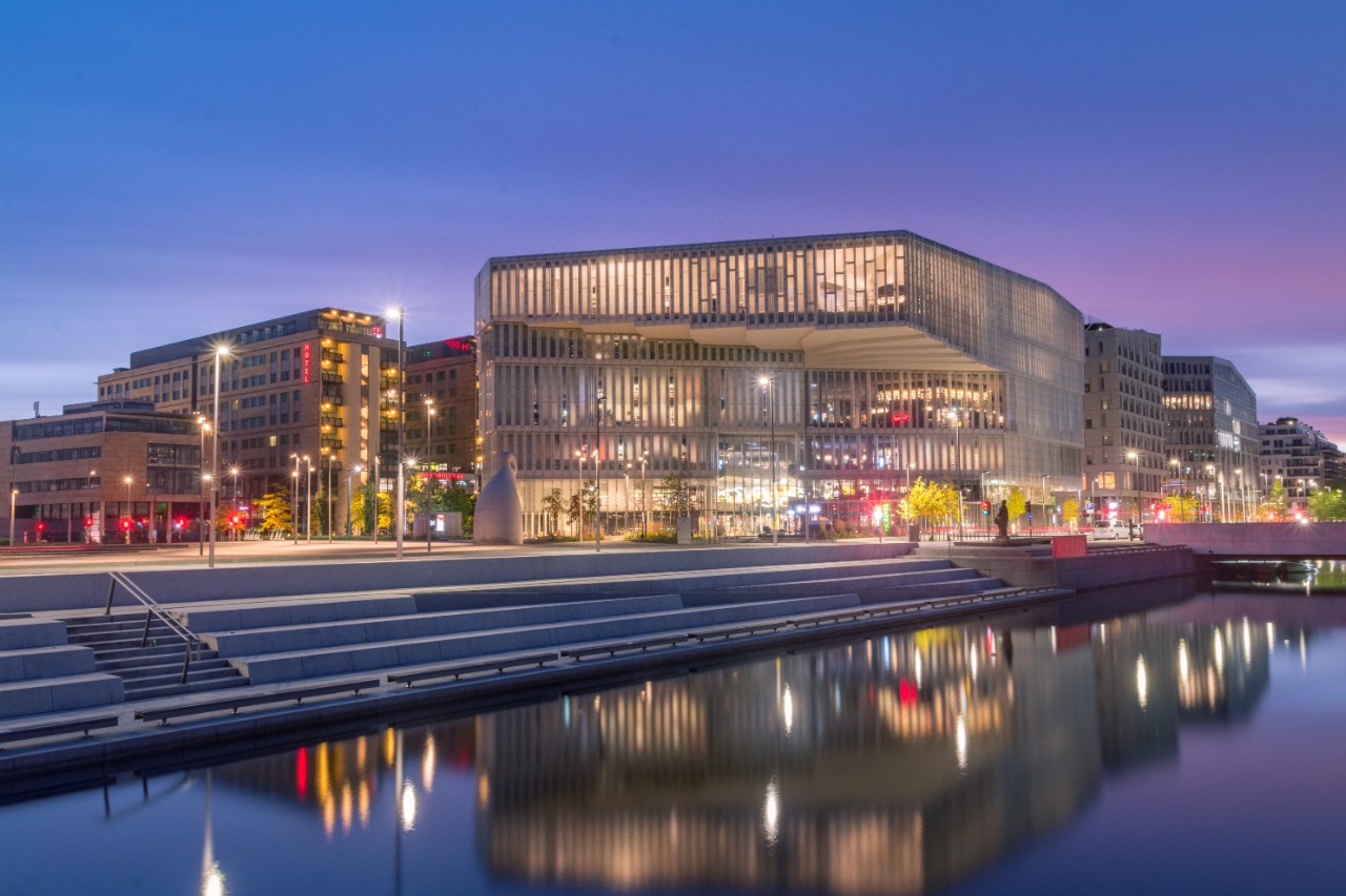 Deichman Library in Bjørvika brightly lit in the evening.