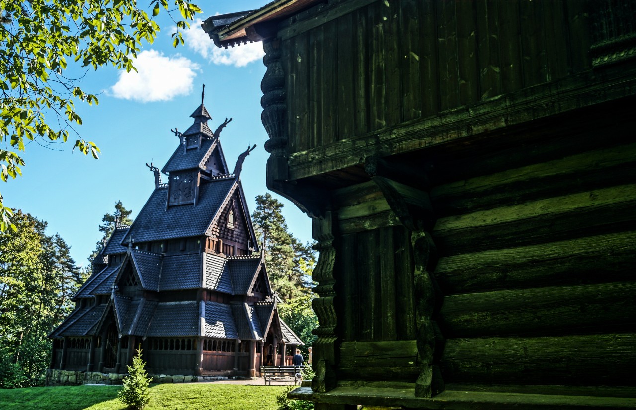 Historic stave church in open-air museum with wooden façade and steep roof.