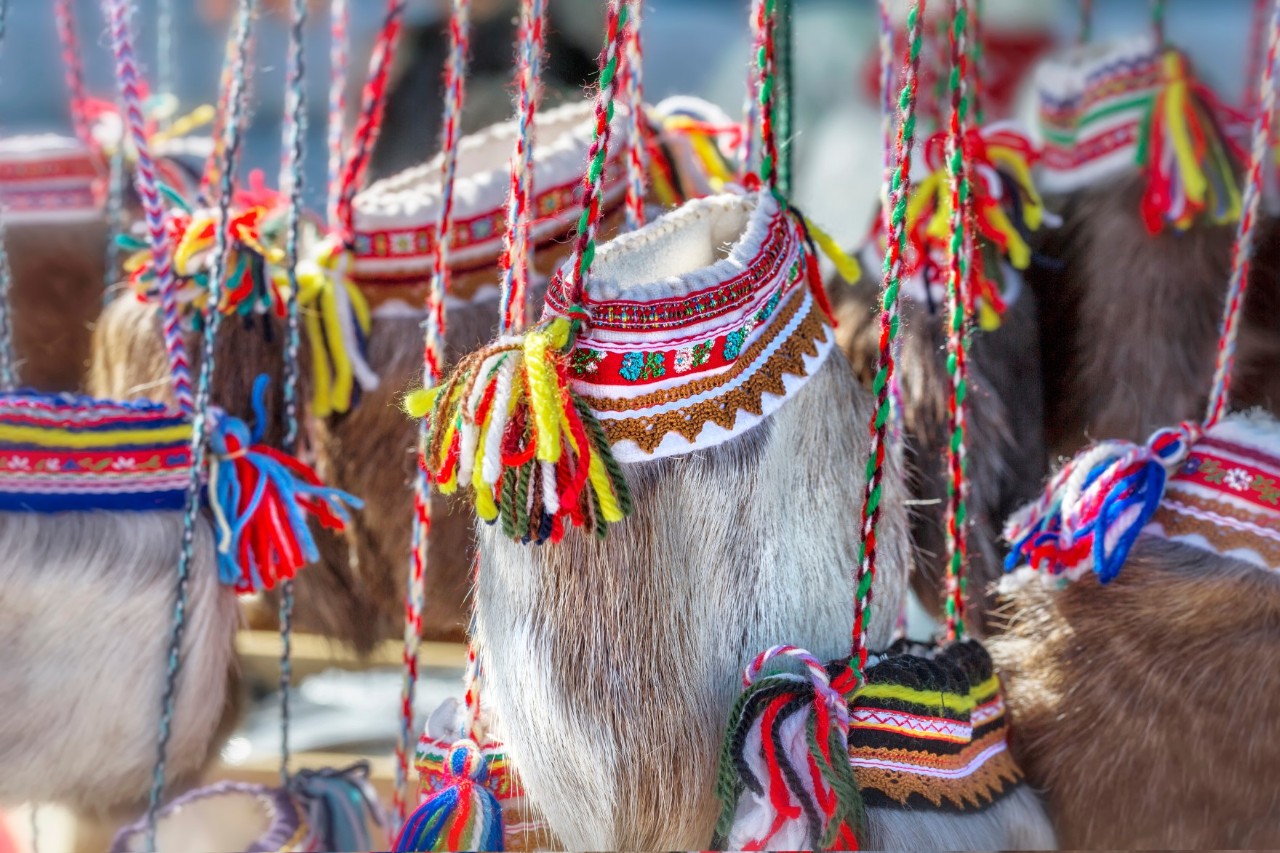 Reindeer skin bags with colourful, hand-woven ribbons and fringes hanging side by side.