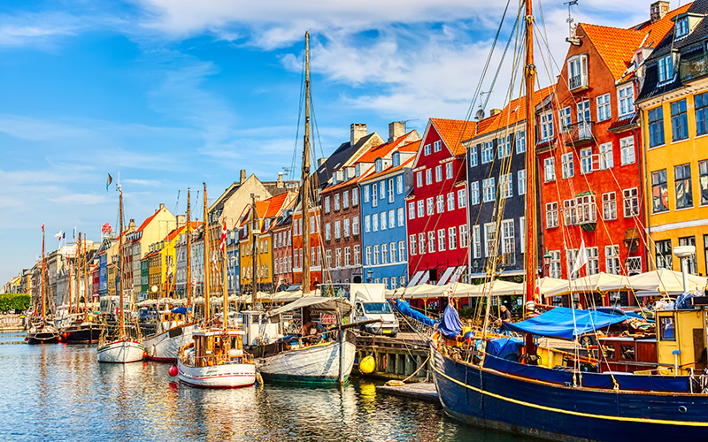 Sailboats in the harbor. Behind it, colorful house facades.