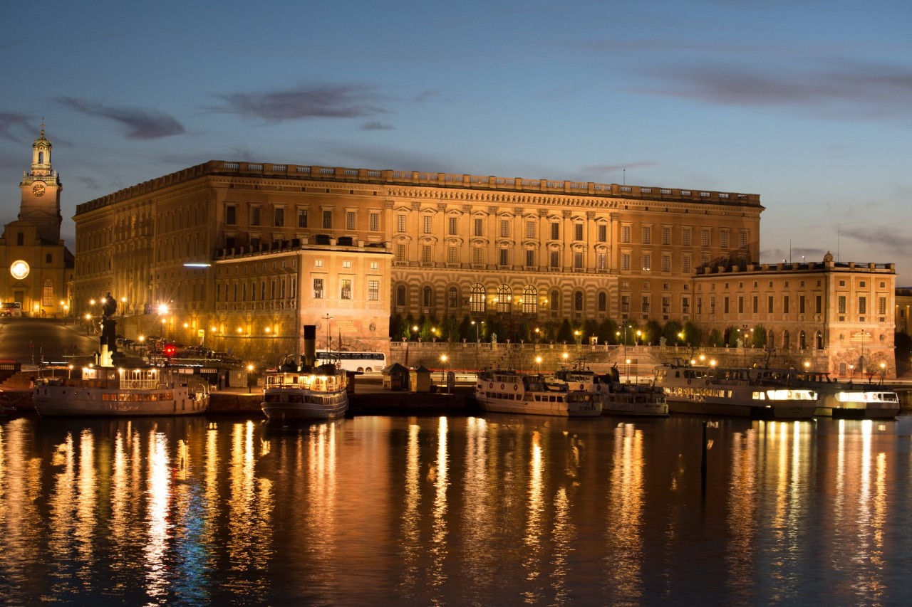 Royal Palace at dusk with boats reflected in the calm water in central Stockholm.