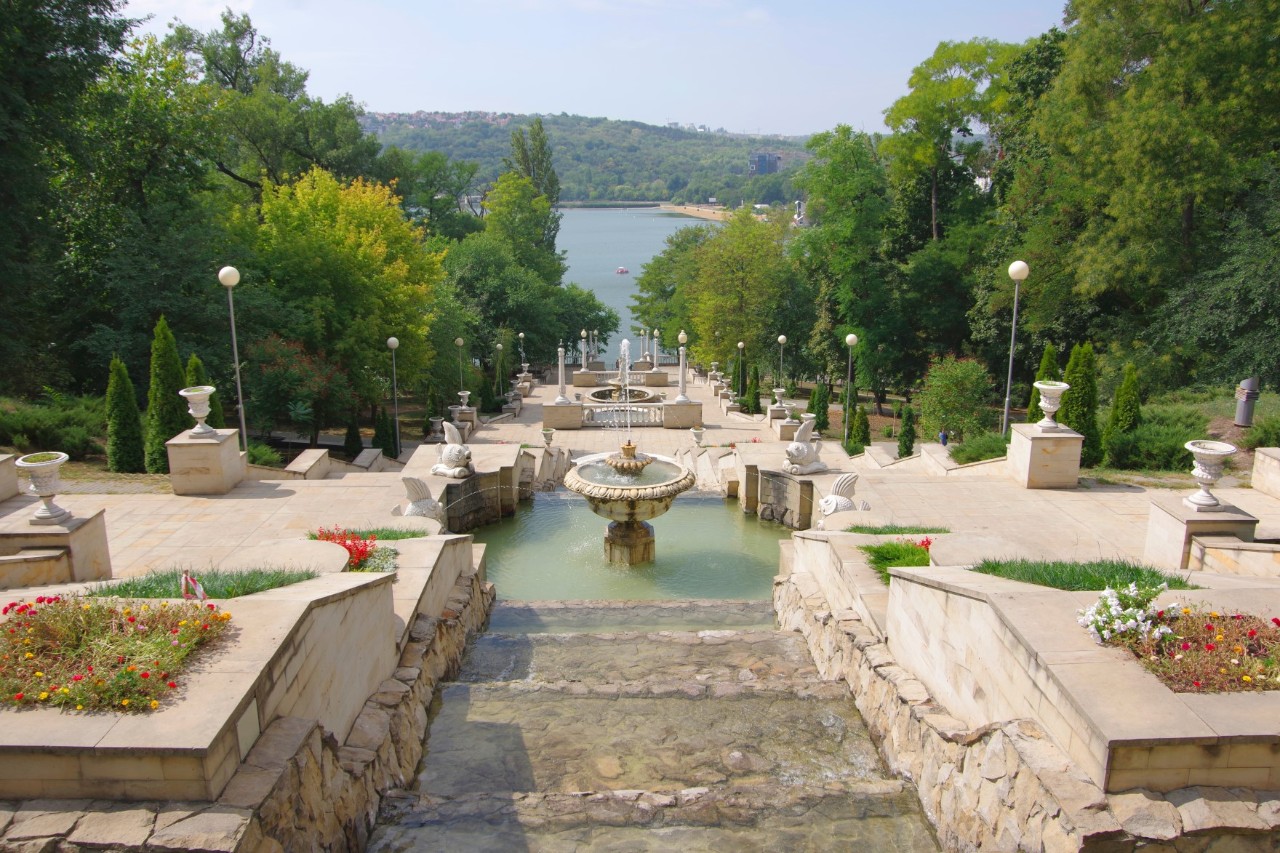 Valea Morilor Park with fountain, steps, vases, flowers, trees and river in the background 