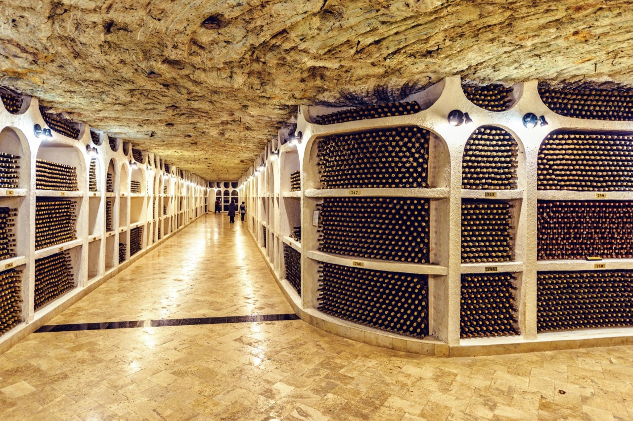 Cricova winery, wine bottles stored in stone shelves, long wooden corridor, stone ceiling 