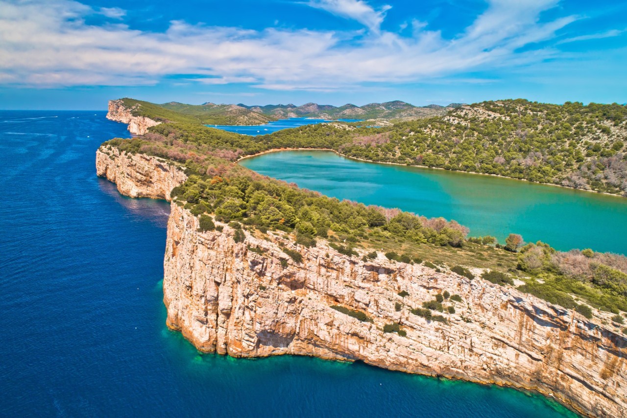 An island with a high cliff rises out of the sea. In the centre of the green island is a large lake and next to it a somewhat smaller, turquoise-blue lake.