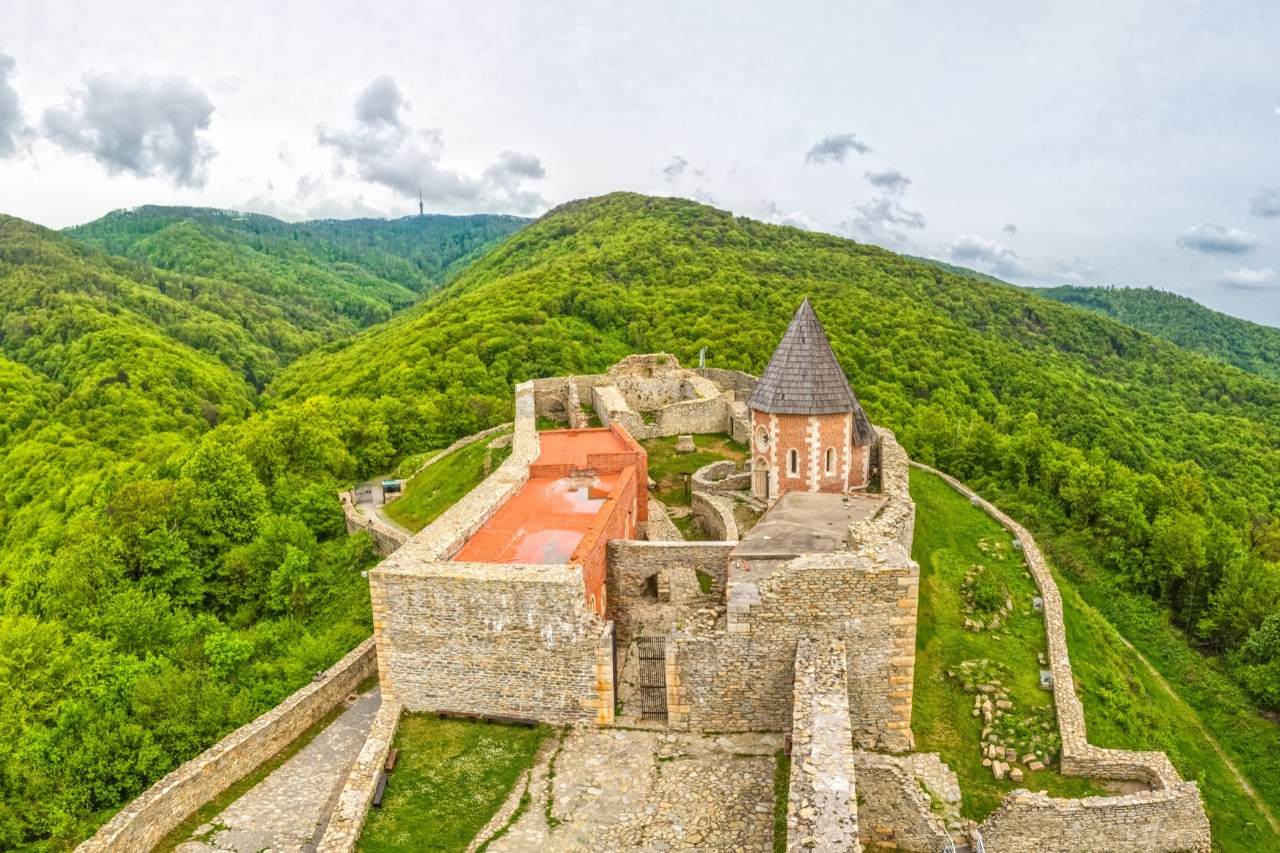Castle with walls and tower surrounded by a green mountain landscape © Dario Bajurin/stock.adobe.com 