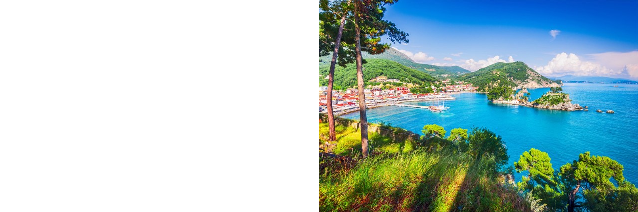 Coastal landscape with a small town by the sea. The houses have red roofs. The turquoise blue sea is surrounded by green hills and small islands.