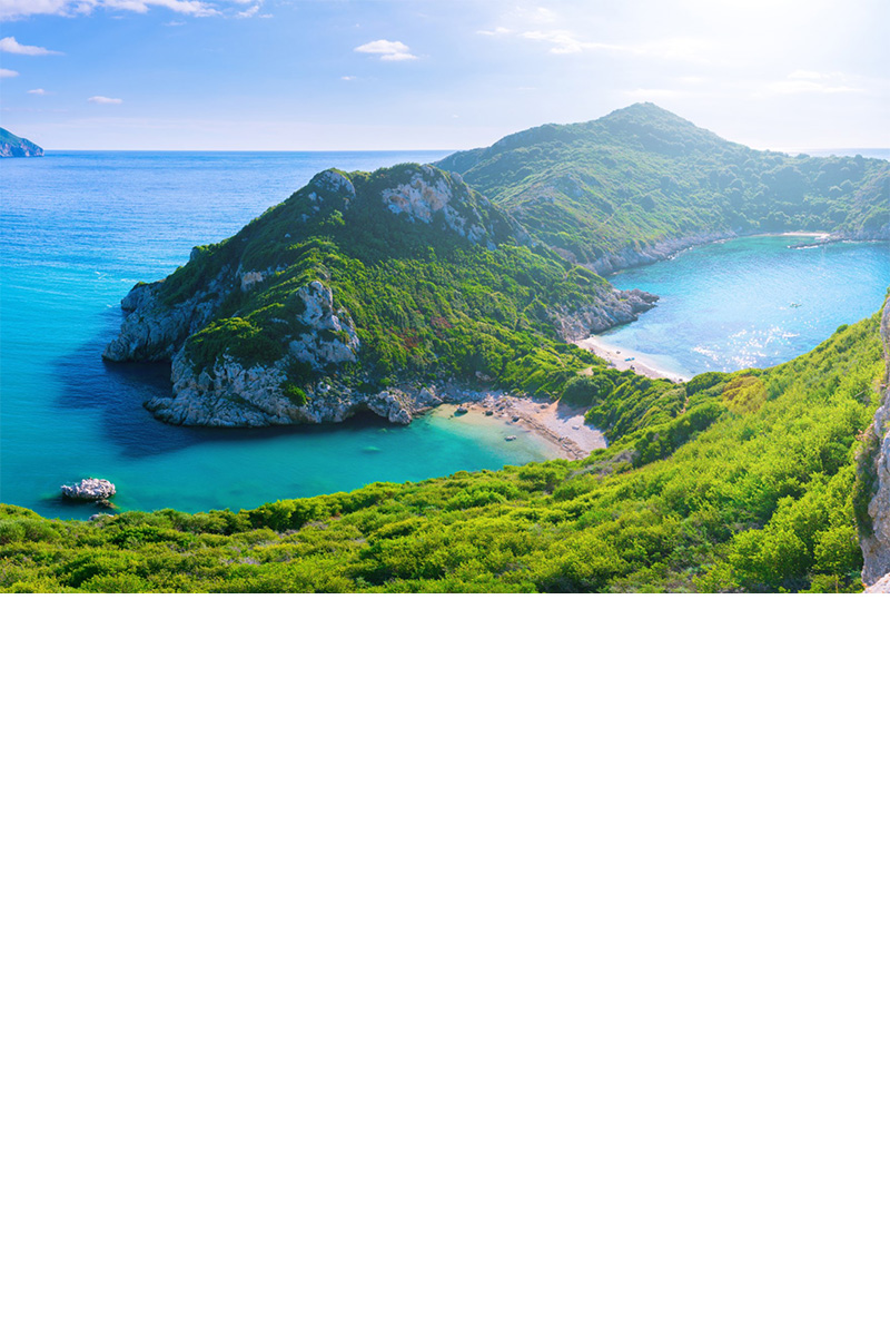 Bathing bay on Corfu. Light blue water and beach. Mountainous terrain.