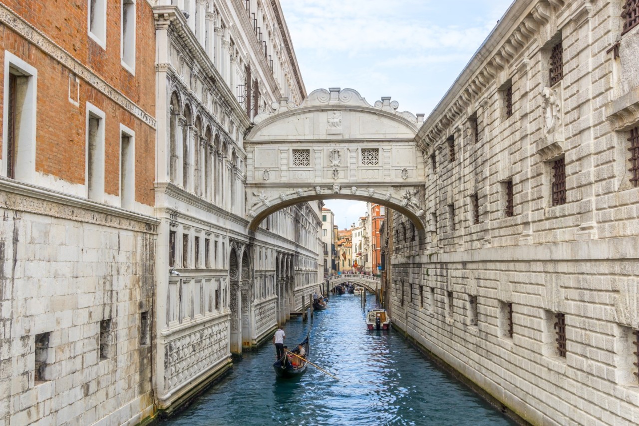 White limestone Bridge of Sighs between the Doge's Palace and the historic prison, including a canal with gondolas and gondoliers. © luili/stock.adobe.com 