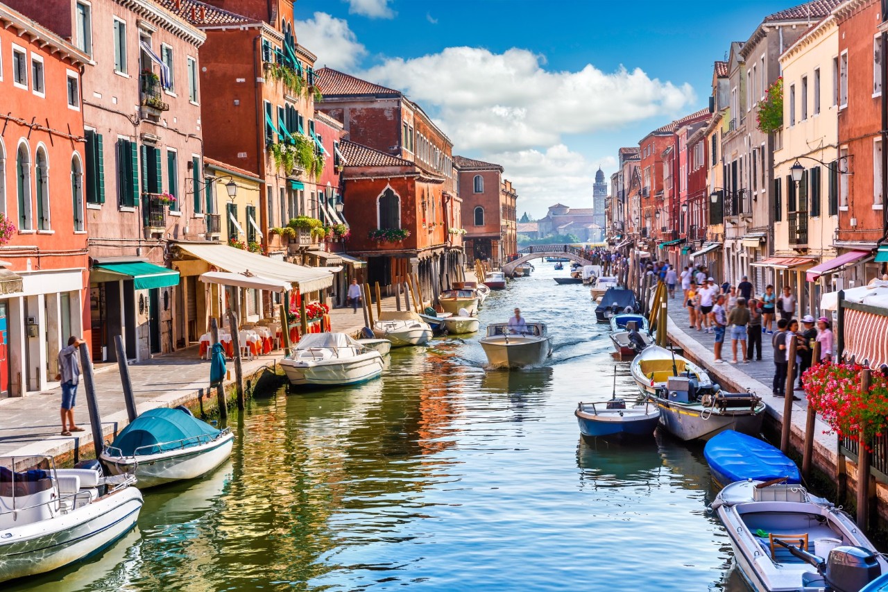 Canal in Murano, right and left colorful houses, boats, pedestrians. © Yasonya/stock.adobe.com 