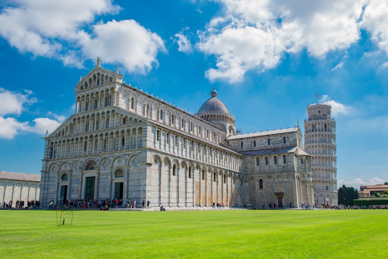 View across an expansive lawn to a cathedral built of white marble, with a leaning tower behind it on the right 