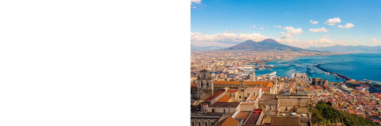 Aerial view of Naples, the Old Town and buildings in the foreground, the sea on the right, Mount Vesuvius on the horizon and cumulus clouds in the sky. © pfeifferv/stock.adobe.com