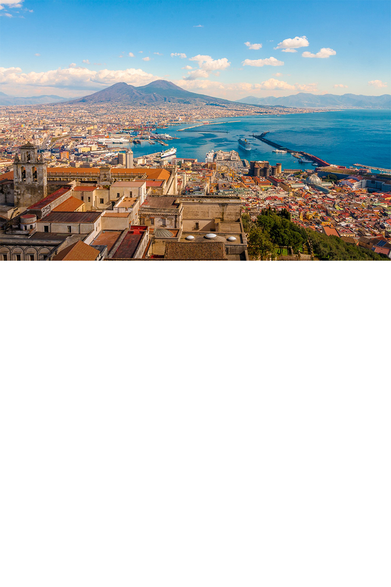 Luftansicht von Neapel, im Vordergrund sind die Altstadt und Häuser, rechts das Meer, am Horizont zeichnet sich der Vesuv ab, Himmel mit Cumulus-Wolken. © pfeifferv/stock.adobe.com