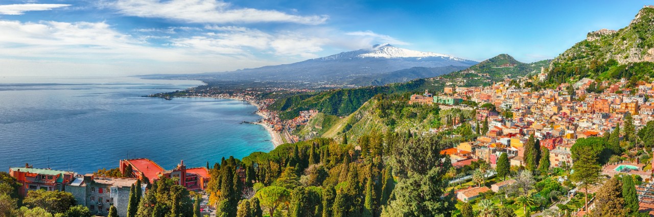 View of the town of Taormina on the island of Sicily in the Mediterranean with the snow-capped volcano Etna in the background © pilat666/stock.adobe.com