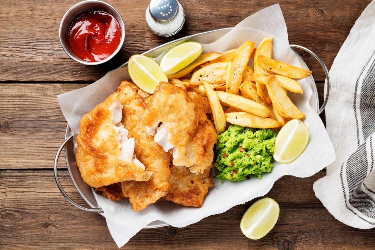 Top view of fish and chips with lemon slice and peas.