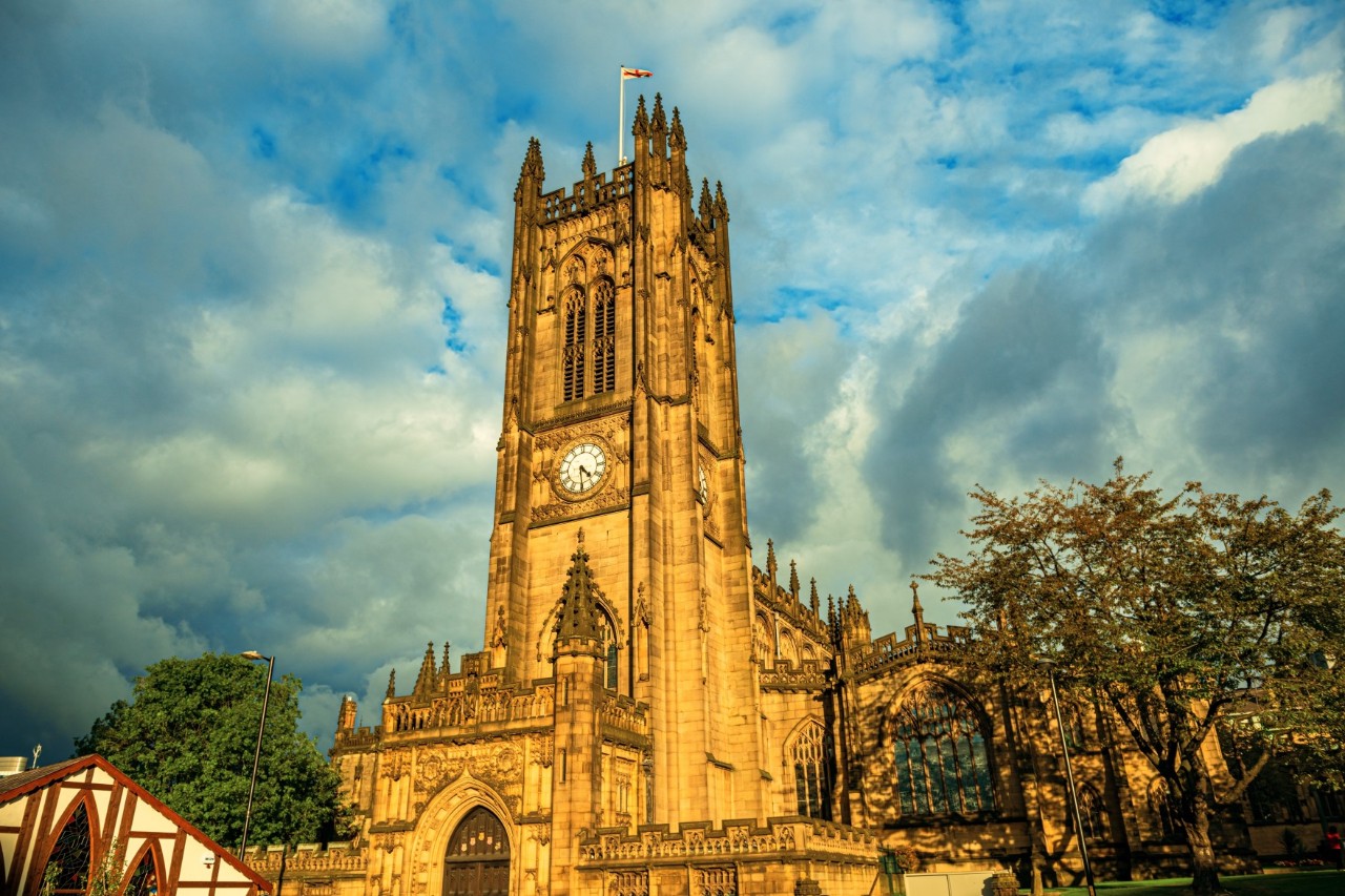 Cathedral in late Gothic style, surrounded by trees, cloudy sky 