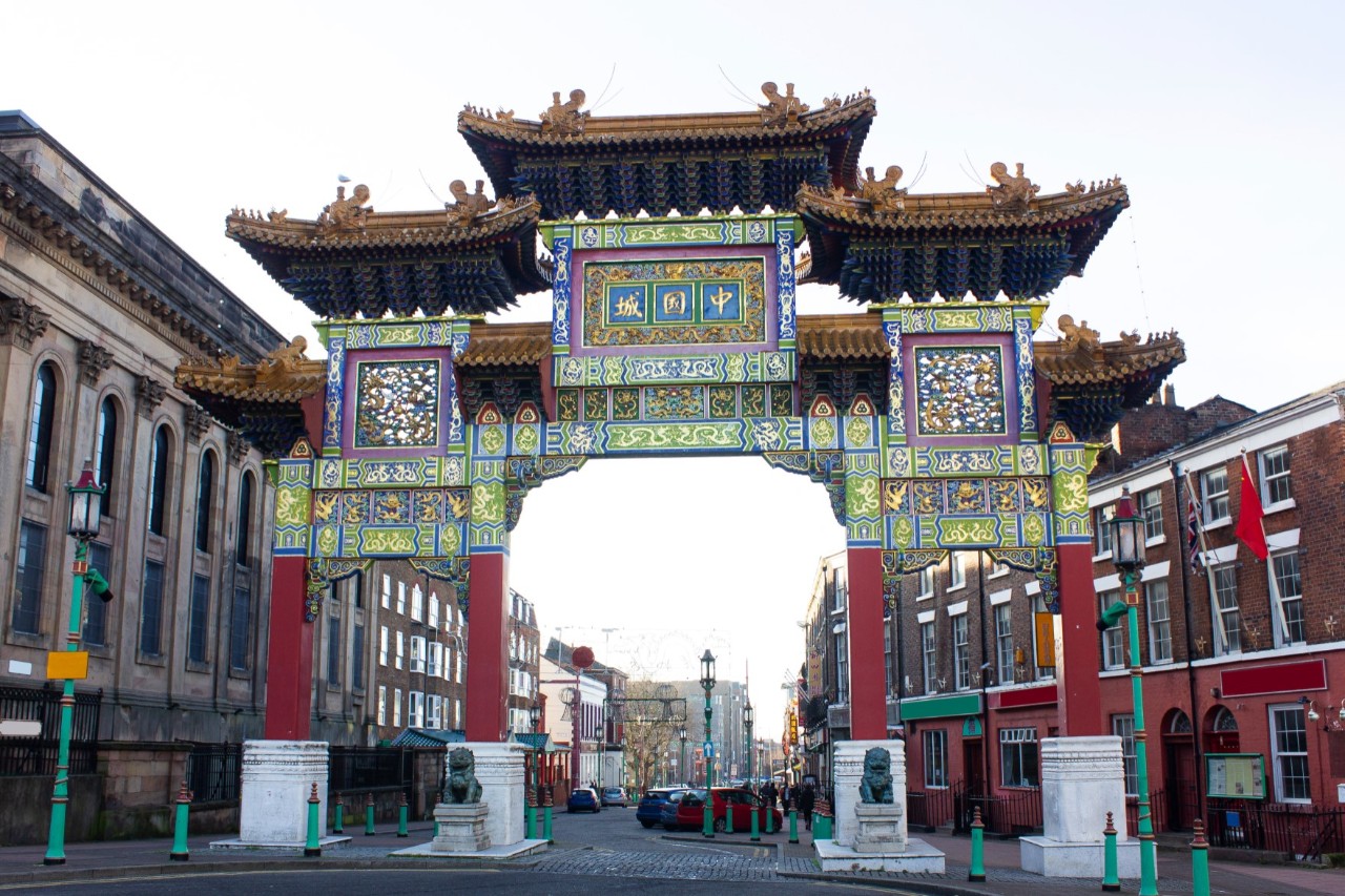Traditional Chinese entrance gate with Chinese characters in Chinatown, adjacent houses © Gheorghe/stock.adobe.com