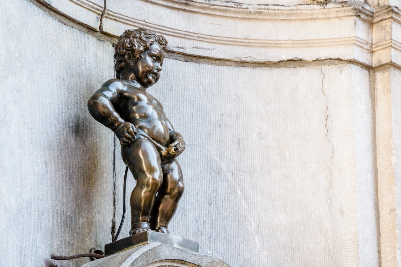 Bronze statue of Manneken Pis in front of a white marble wall © olrat/stock.adobe.com 