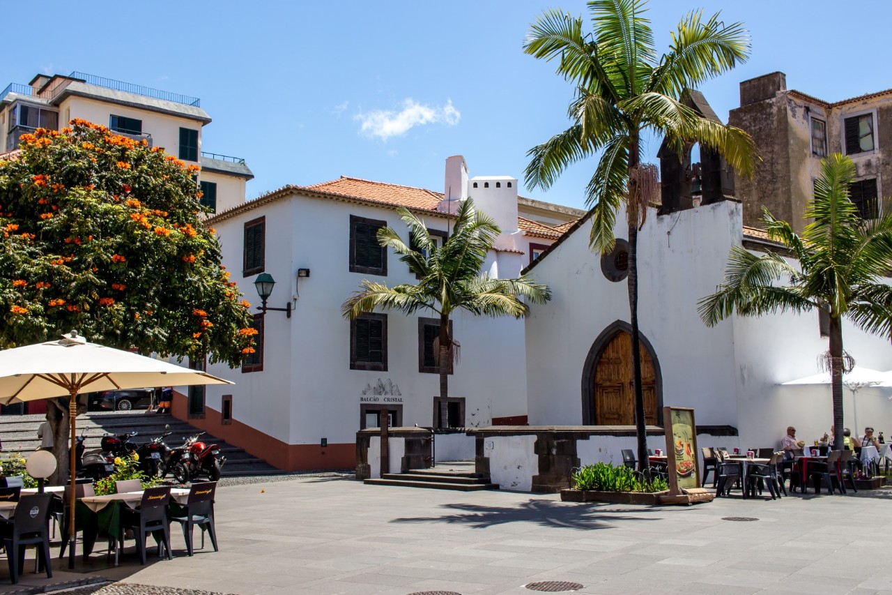 Public square in the old town centre with street cafés, palm trees and white buildings 